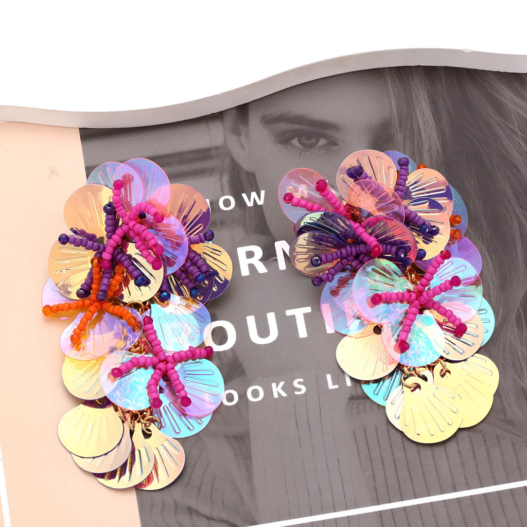 Close-up of handmade purple and green bead flower earrings with leaf details on a white background.