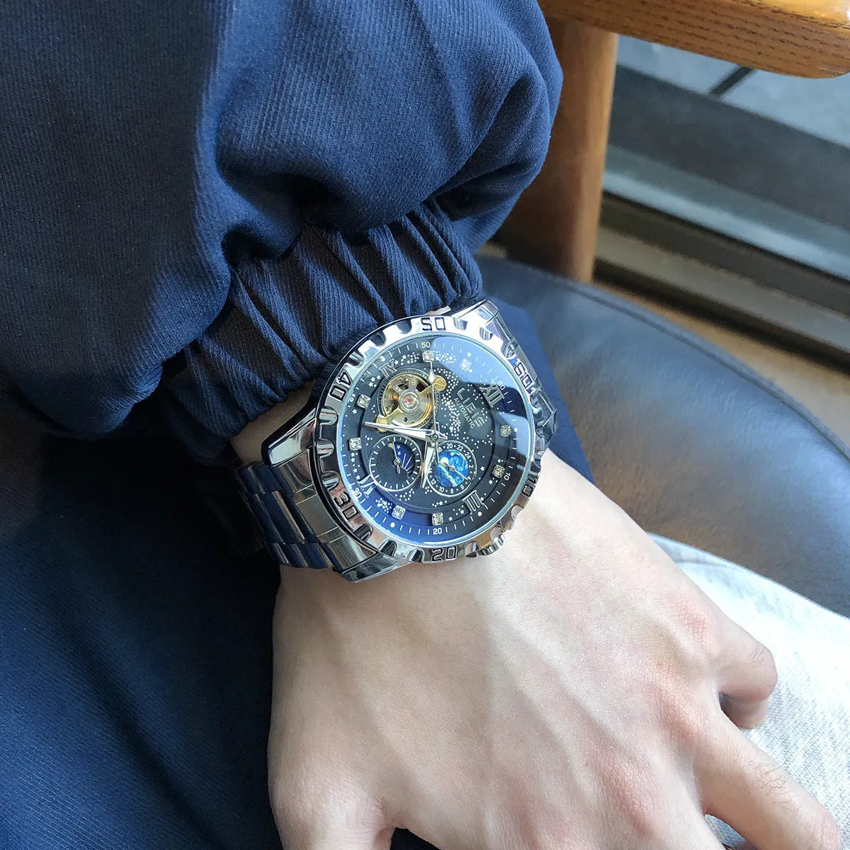 Men's silver case automatic watch with black starry dial, luminous hands, and brown leather strap