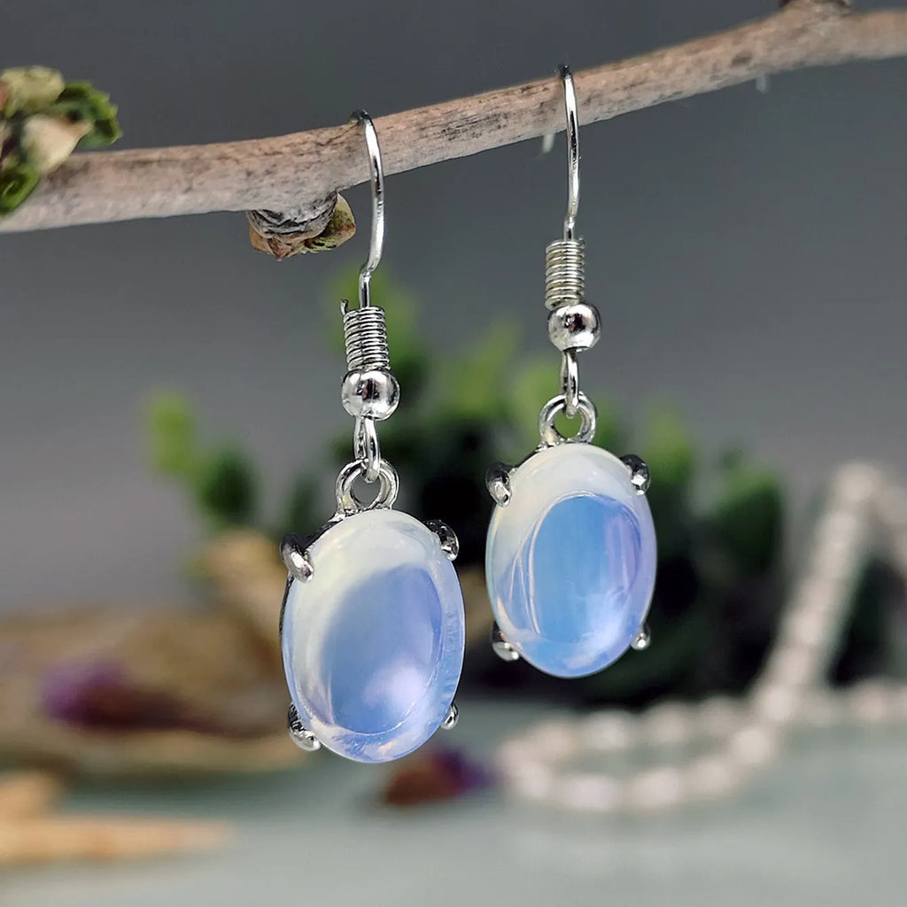 Moonlight white opal earrings with cross pendant and drop shape on retro moonstone style background