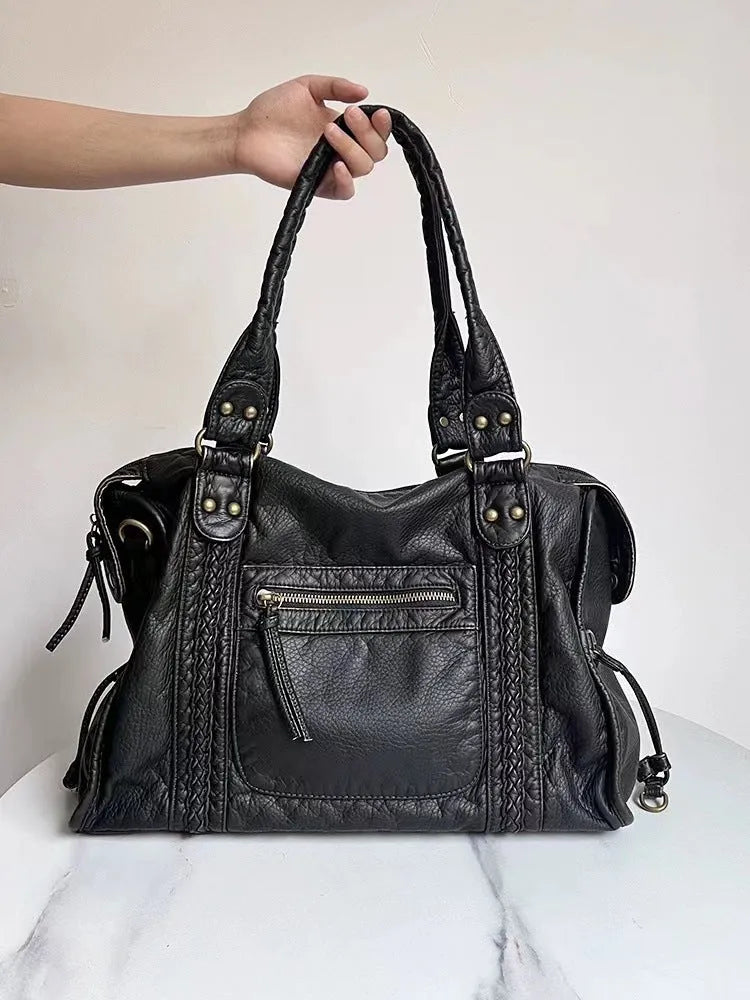 Women's retro motorcycle style messenger bag in bright black with golden edge, showing internal zipper compartments and single shoulder strap