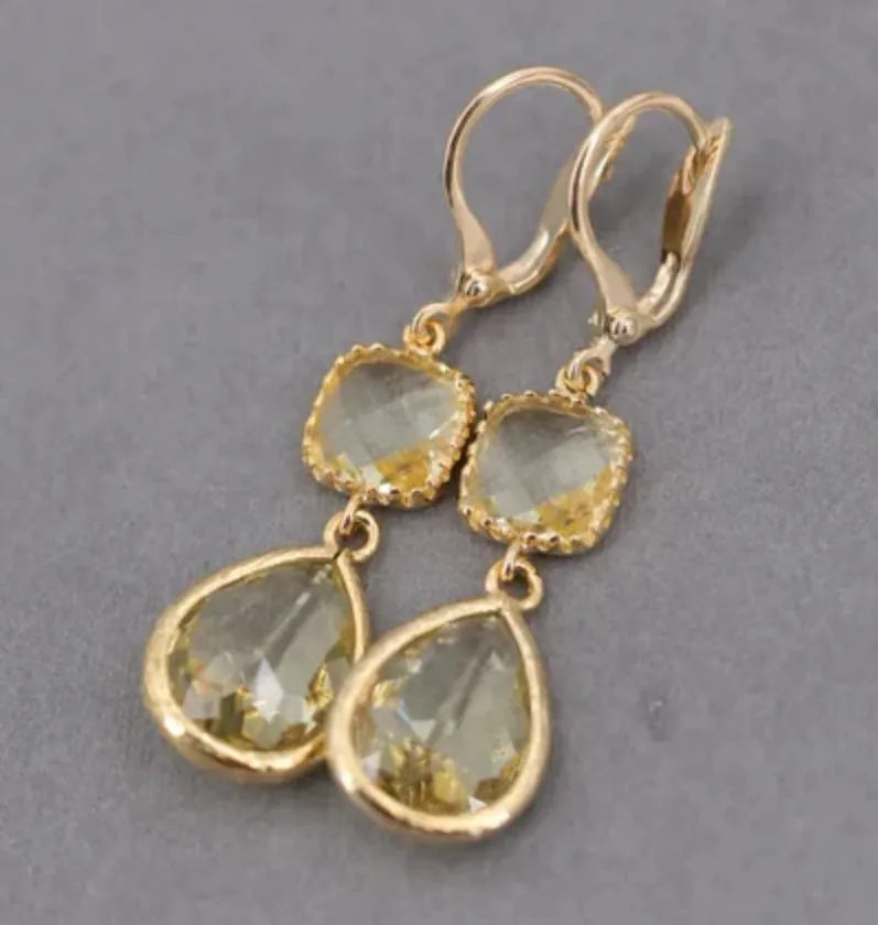 Gold geometric long fringe drop earrings with crystal and water droplet details on a white background.