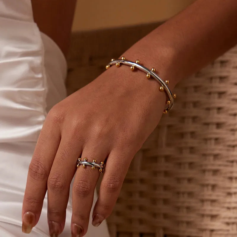 Stainless steel C-shaped bean bead charm with round rivet texture, shown in gold, steel, and steel gold colours.