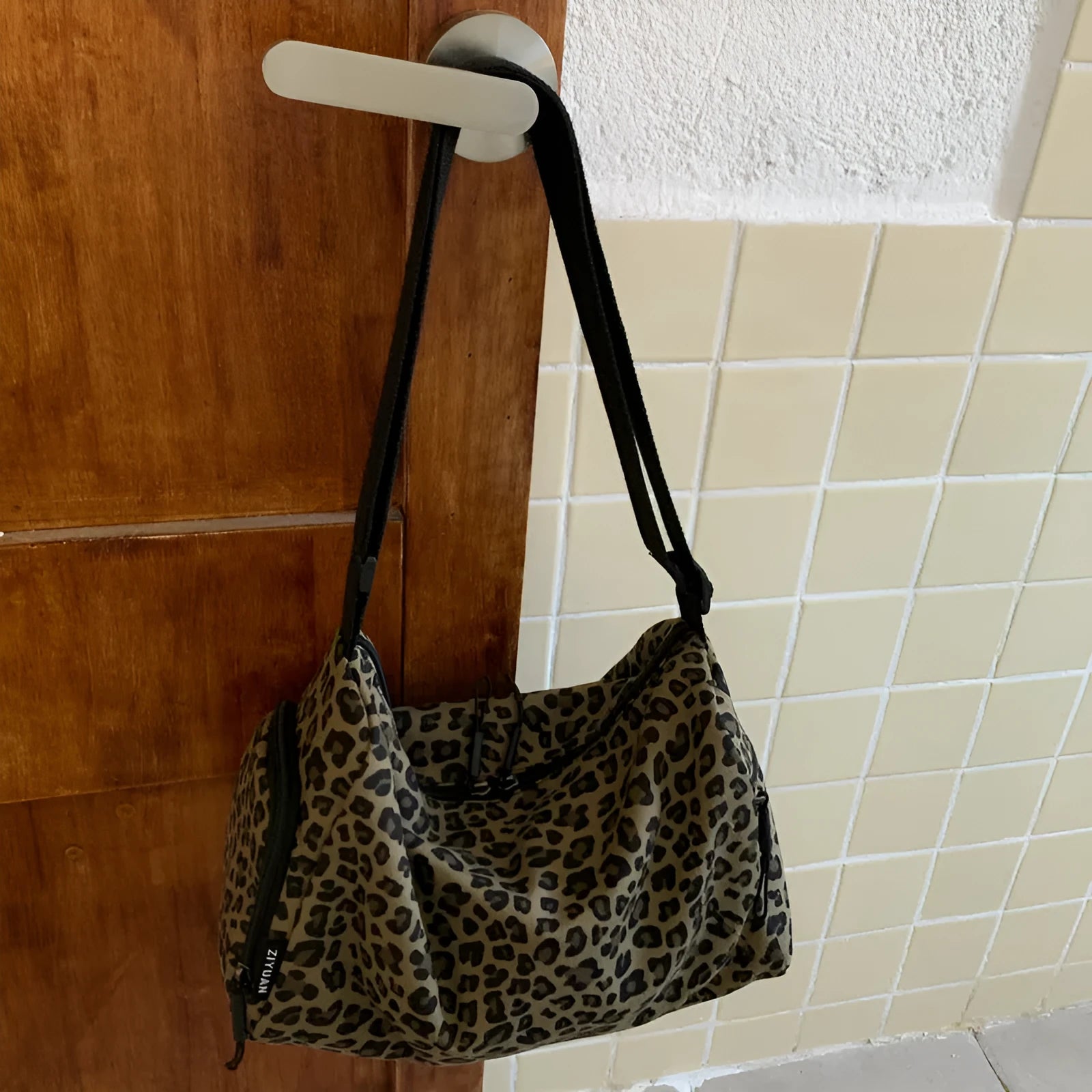 Leopard print cross-body messenger bag with shoulder strap and stitching details