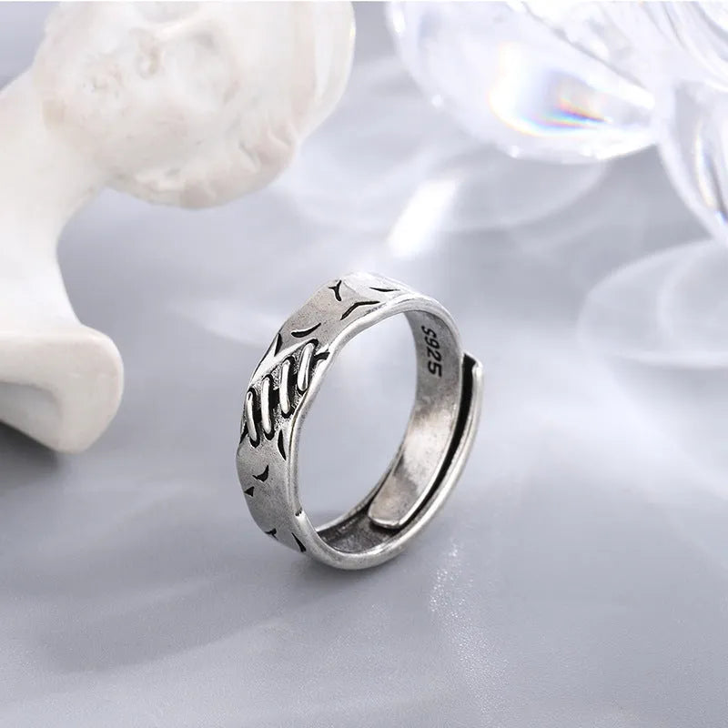Black geometric copper ring with an adjustable opening on a white background.