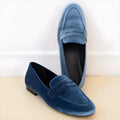 Blue flat suede loafers with black rubber sole, round toe, and low-top slip-on design