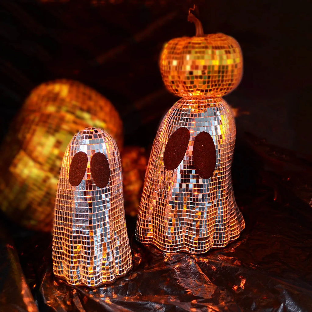 Silver glass Halloween ghost ornament with mosaic inlaid surface on a desktop.