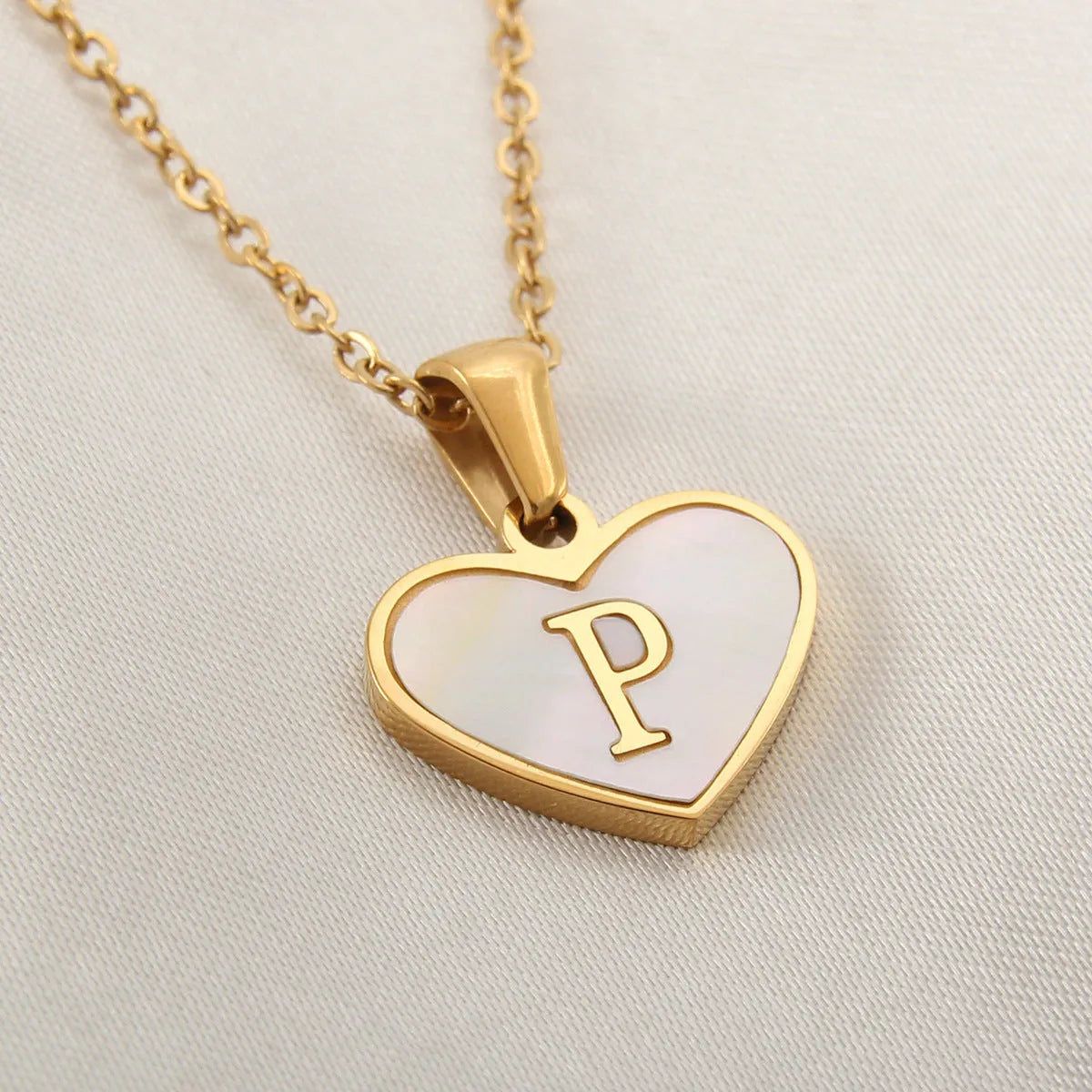 Gold-plated heart necklace with white shell pendant showing initial engraving on stainless steel chain