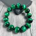 Green Tiger Eye stone geometric bead bracelet on wrist, showing polished surface and banding.