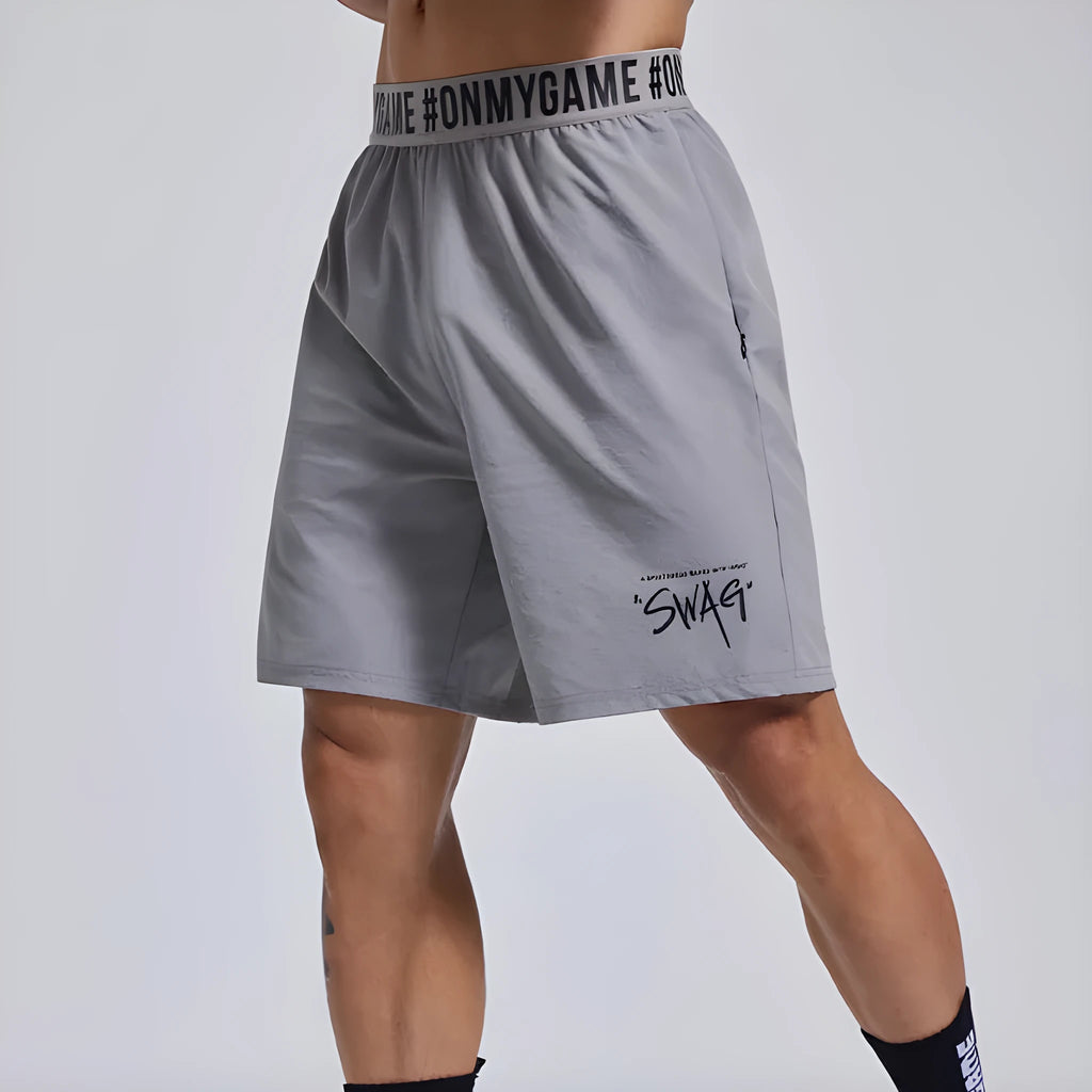 Men's loose black cropped sports shorts with an elastic waistband on a grey background