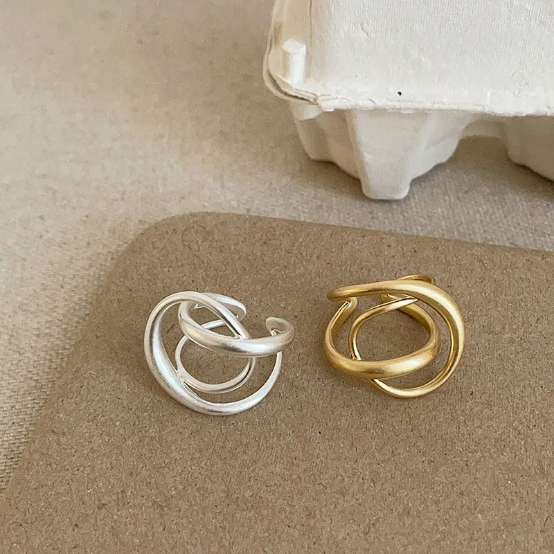 Geometric open ring for women with 3D interlaced matte metal design, shown in gold plating.