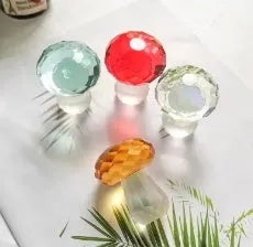 Colourful geometric crystal mushroom decoration in transparent, green, red, or yellow on a white background.