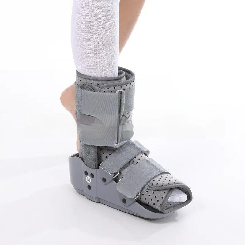 Grey achilles tendon rehabilitation boot with adjustable straps and a rigid plastic shell on a rubber sole.