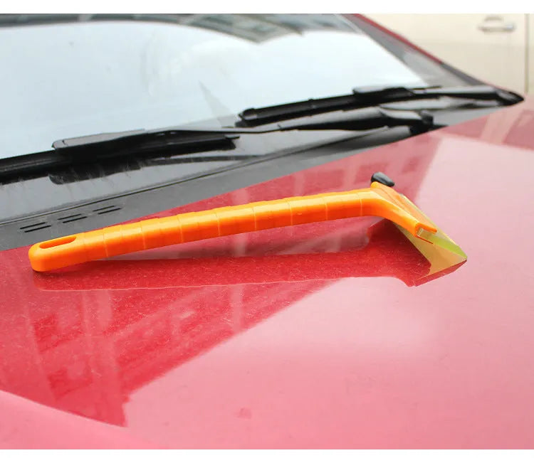 Yellow plastic car snow shovel for ice removal, 32cm length, on a dark background