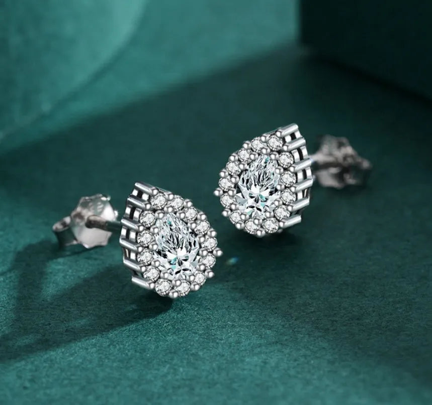 A pair of women's silver water drop shaped stud earrings on a plain background