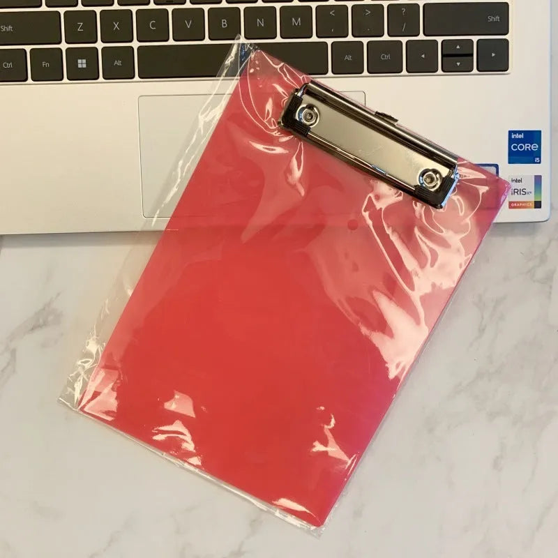 Transparent A4 plate writing board holder with metal clip, shown in blue colour on a desk.