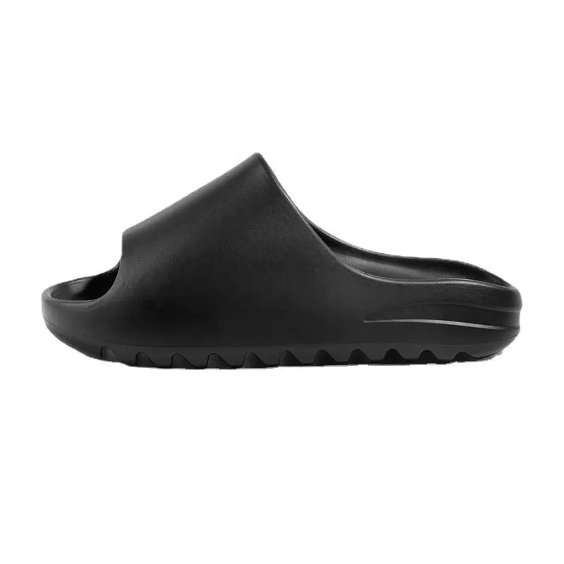 Women's black beach slippers with thick EVA soles on a sandy background.