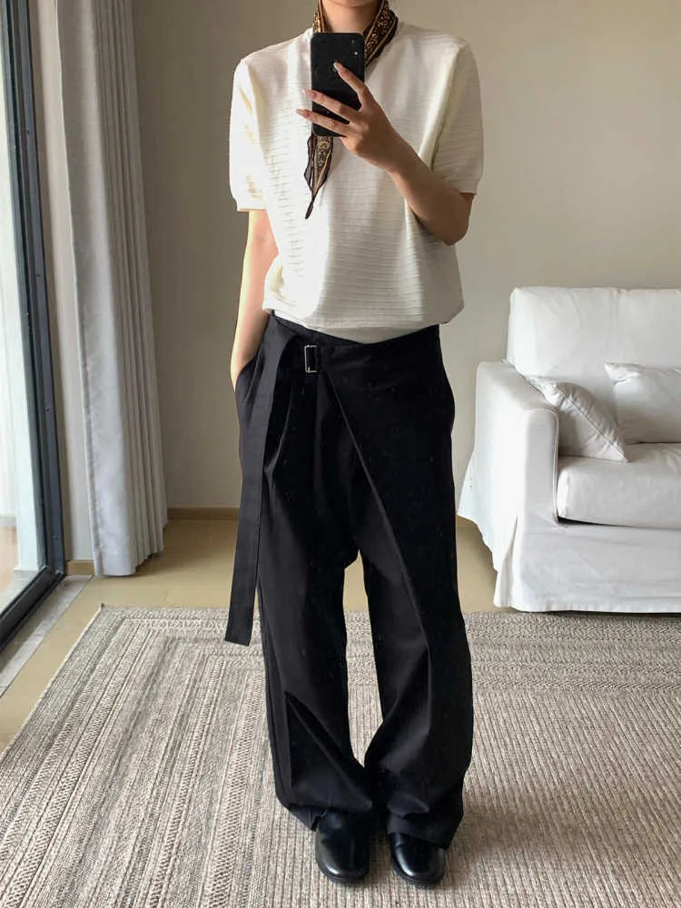Black loose fit straight leg trousers with a single pleat and adjustable waistband on a hanger.