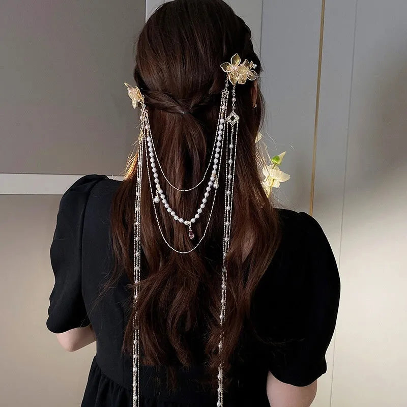 Close-up of a women's floral hairpin with white pearl, clear diamond accents, and a long gold tassel.
