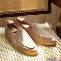 Men's brown genuine leather handmade loafers on a white background, showing the low-cut slip-on design and textured sole.