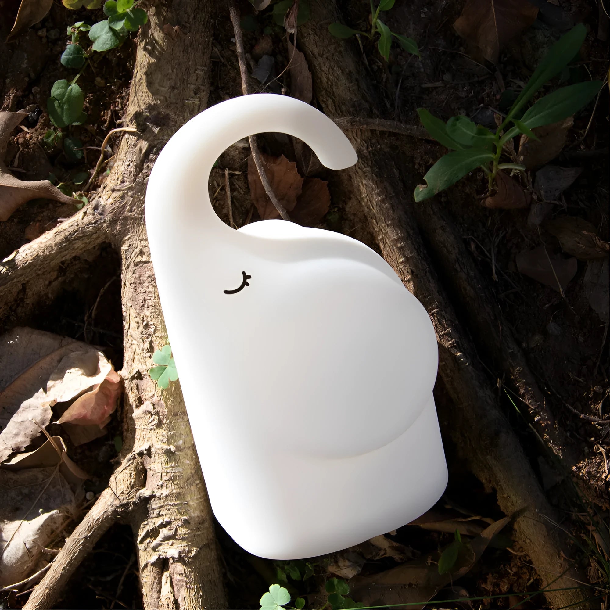 DOMI elephant-shaped silicone night light with warm white glow on a bedside table.