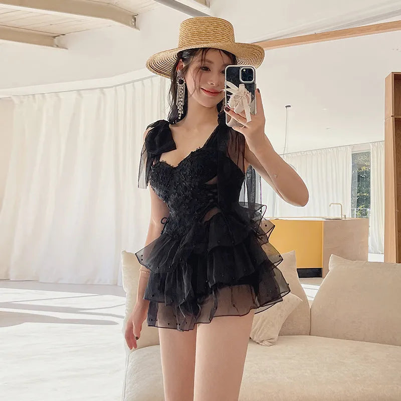 Black one-piece swimsuit with gathered chest on a mannequin, showing conservative cut and sleeveless design.