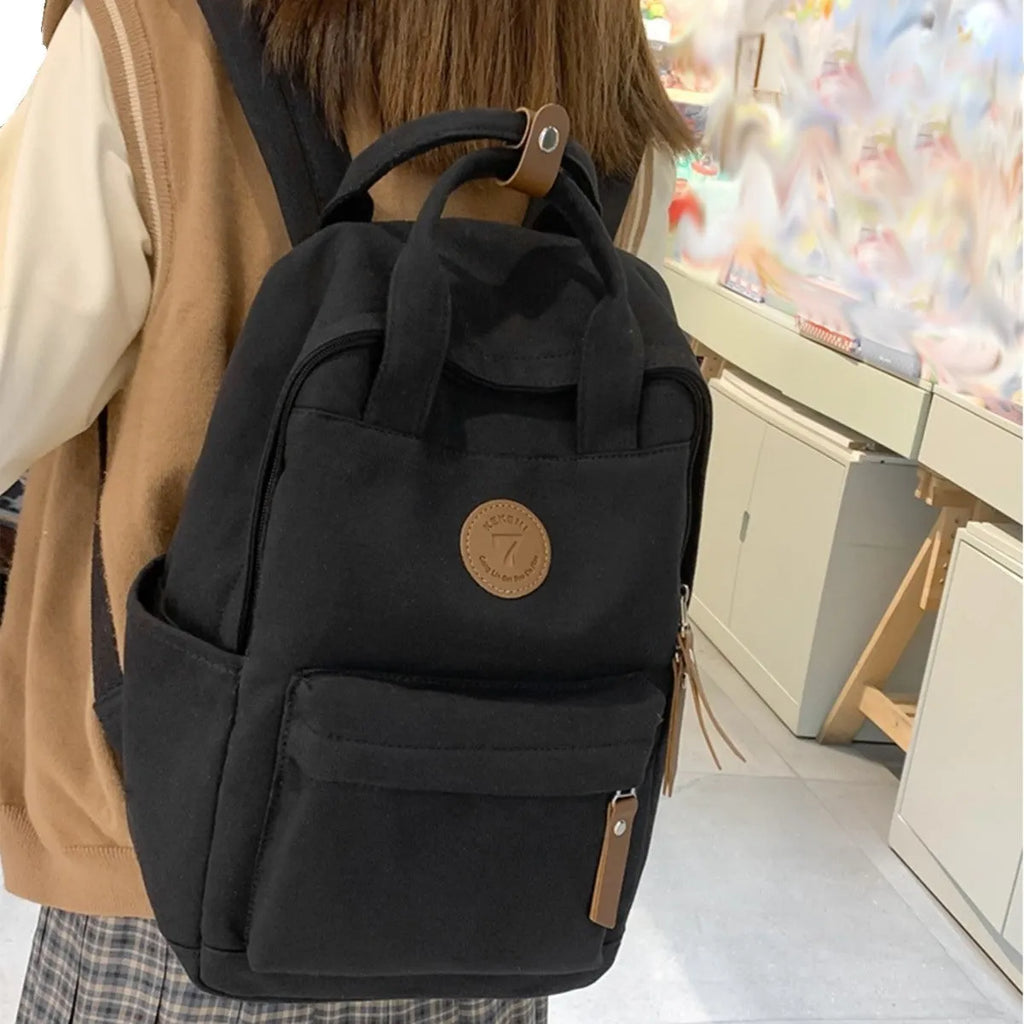 Black Oxford cloth backpack with curved shoulder straps on solid background
