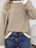 Women's beige loose knit top with green four leaf clover contrast trim on the V-neck and long sleeves.