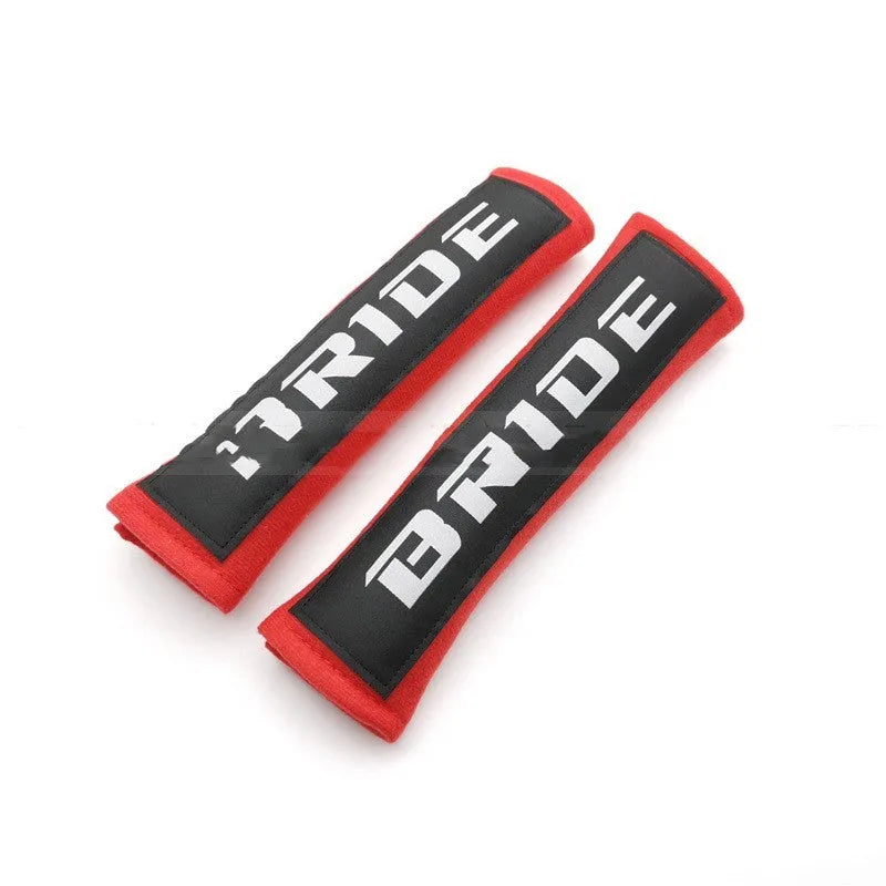 Pair of black car seatbelt shoulder pads showing embroidery detail and thickness