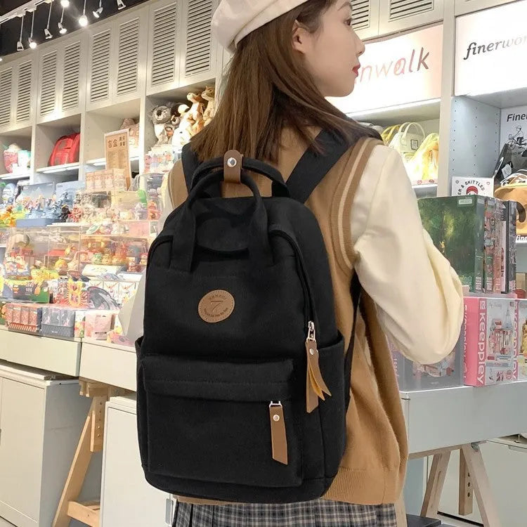 Black Oxford cloth backpack with curved shoulder straps on solid background