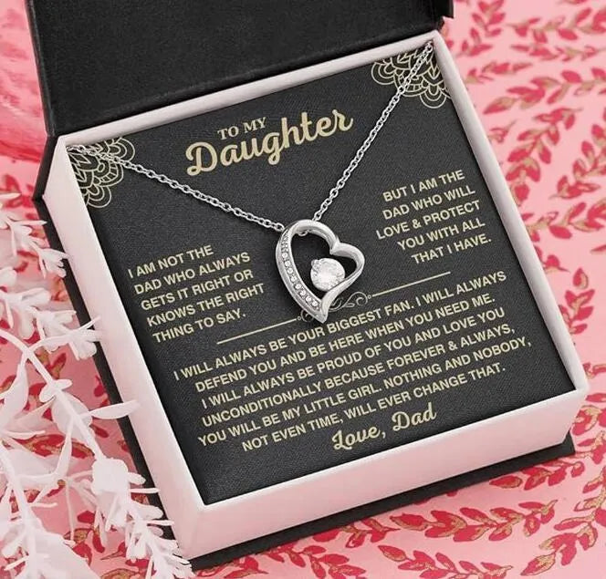 Silver and gold hollow heart necklace pendant presented on a card inside an open gift box.