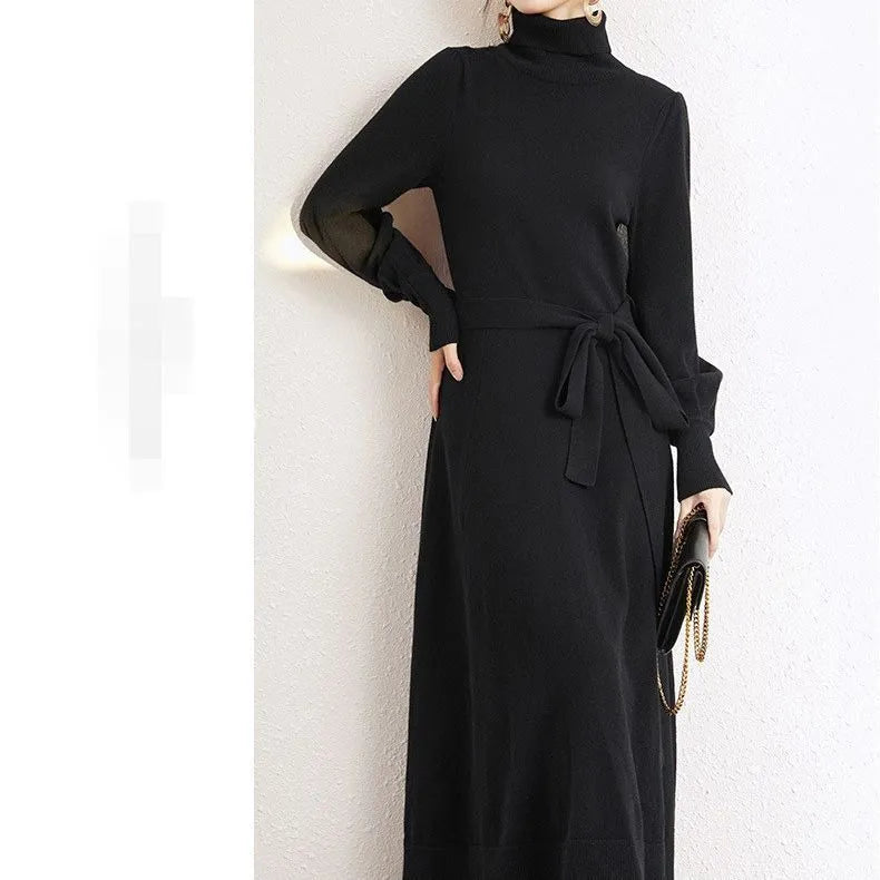 A woman wearing a rose red turtleneck knit dress with long sleeves, an elastic waist, and a loose mid-length hem.