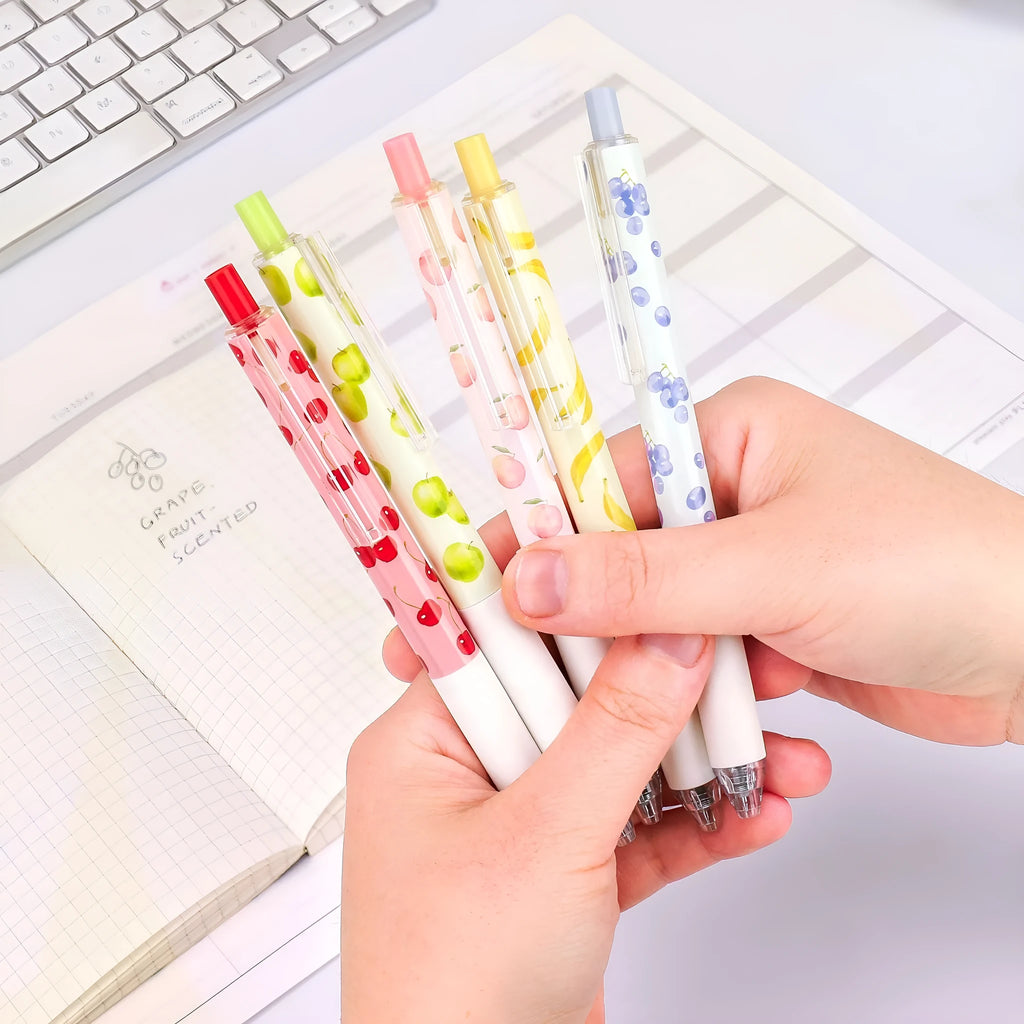 Three fruit scented press-action pens with 0.5mm quick-drying black refills on white background