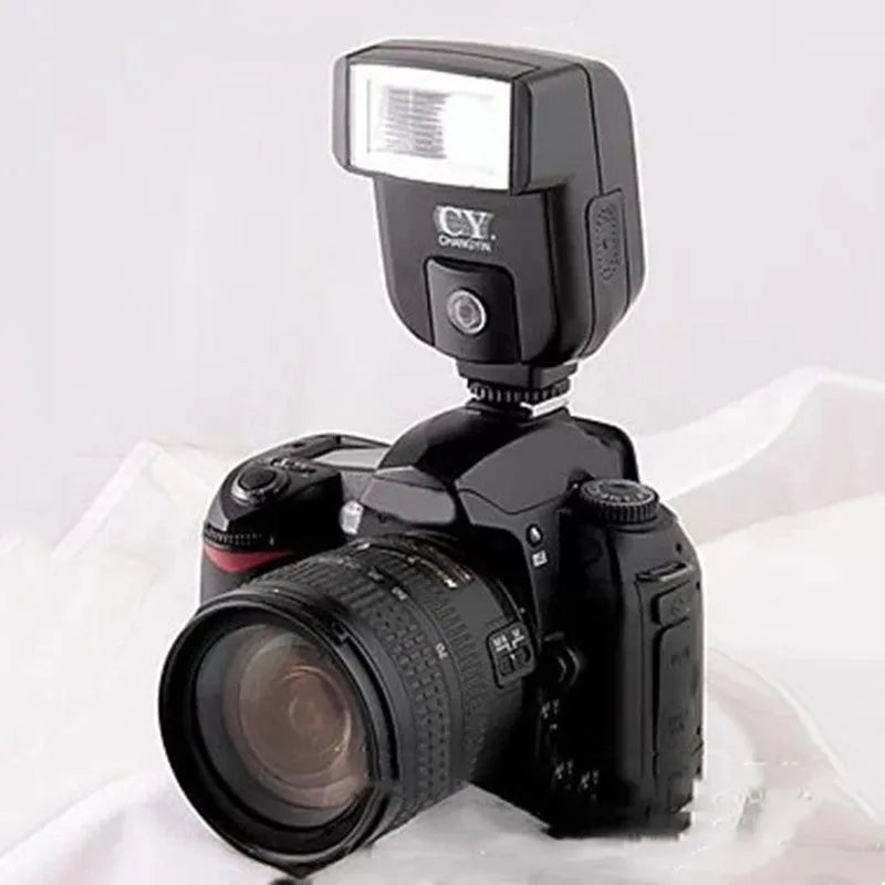 Compact black external camera flashgun with a tilted flash head, shown mounted on an SLR camera hot shoe.