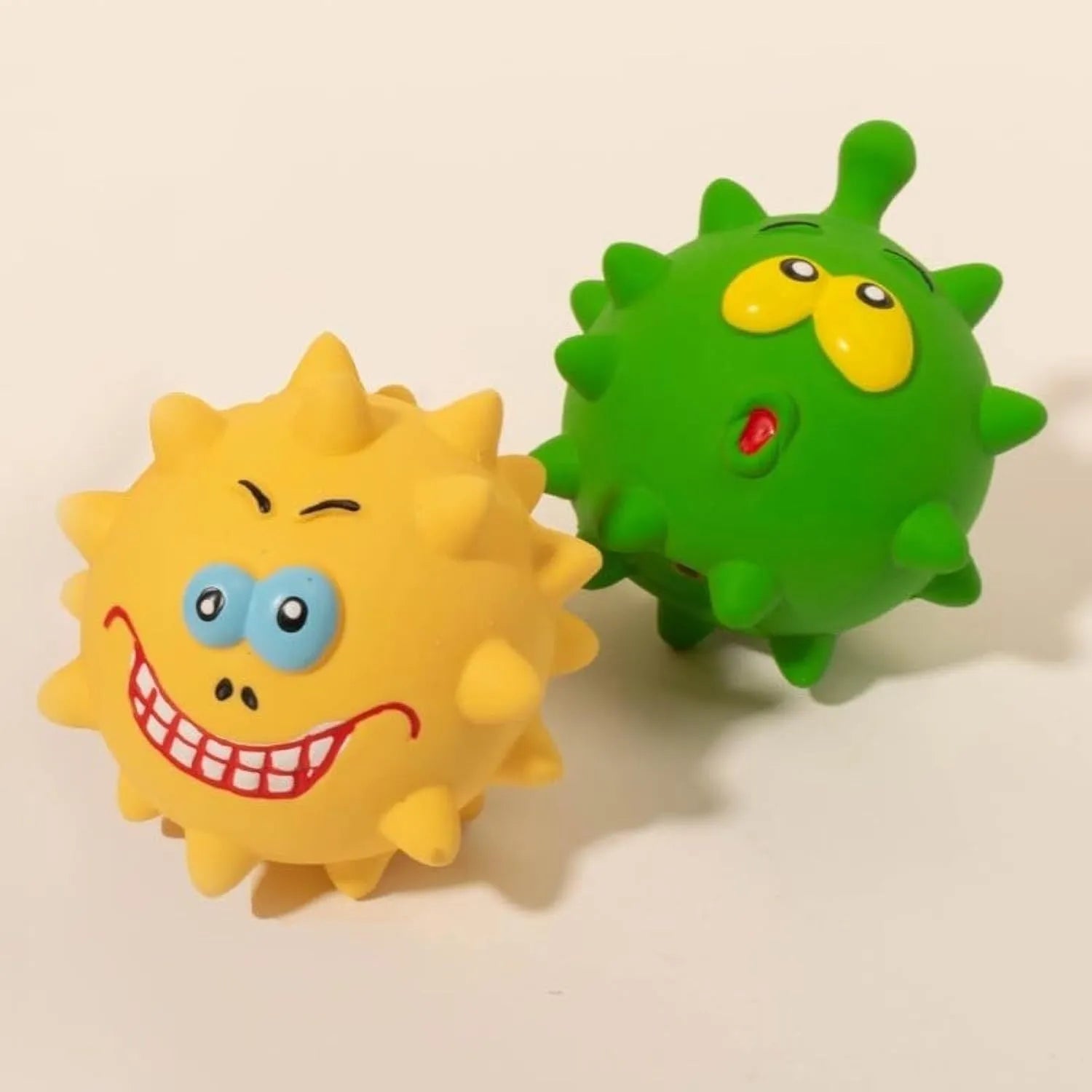 Four colourful squeaky dog balls with textured surfaces and cute faces