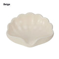 White or pink plastic shell-shaped soap dish with raised design on a bathroom counter.