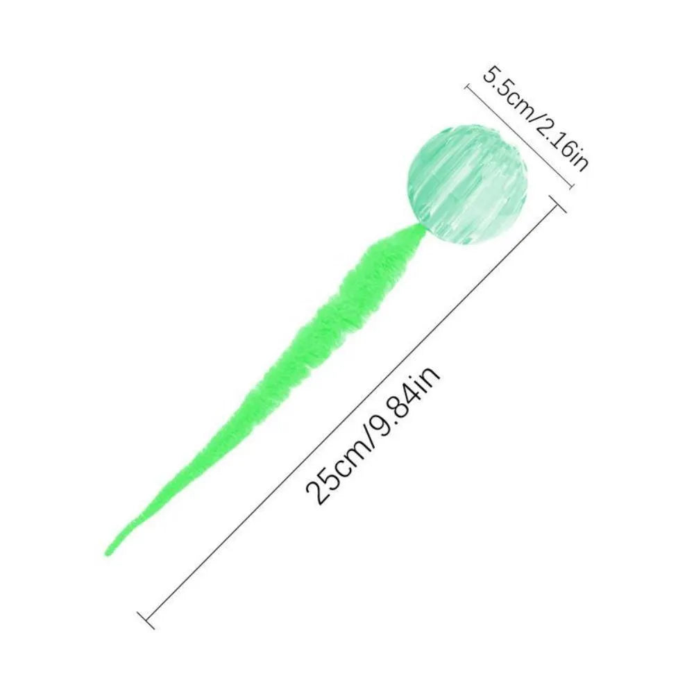 Green bouncy ball cat toy with plush tail on wooden floor