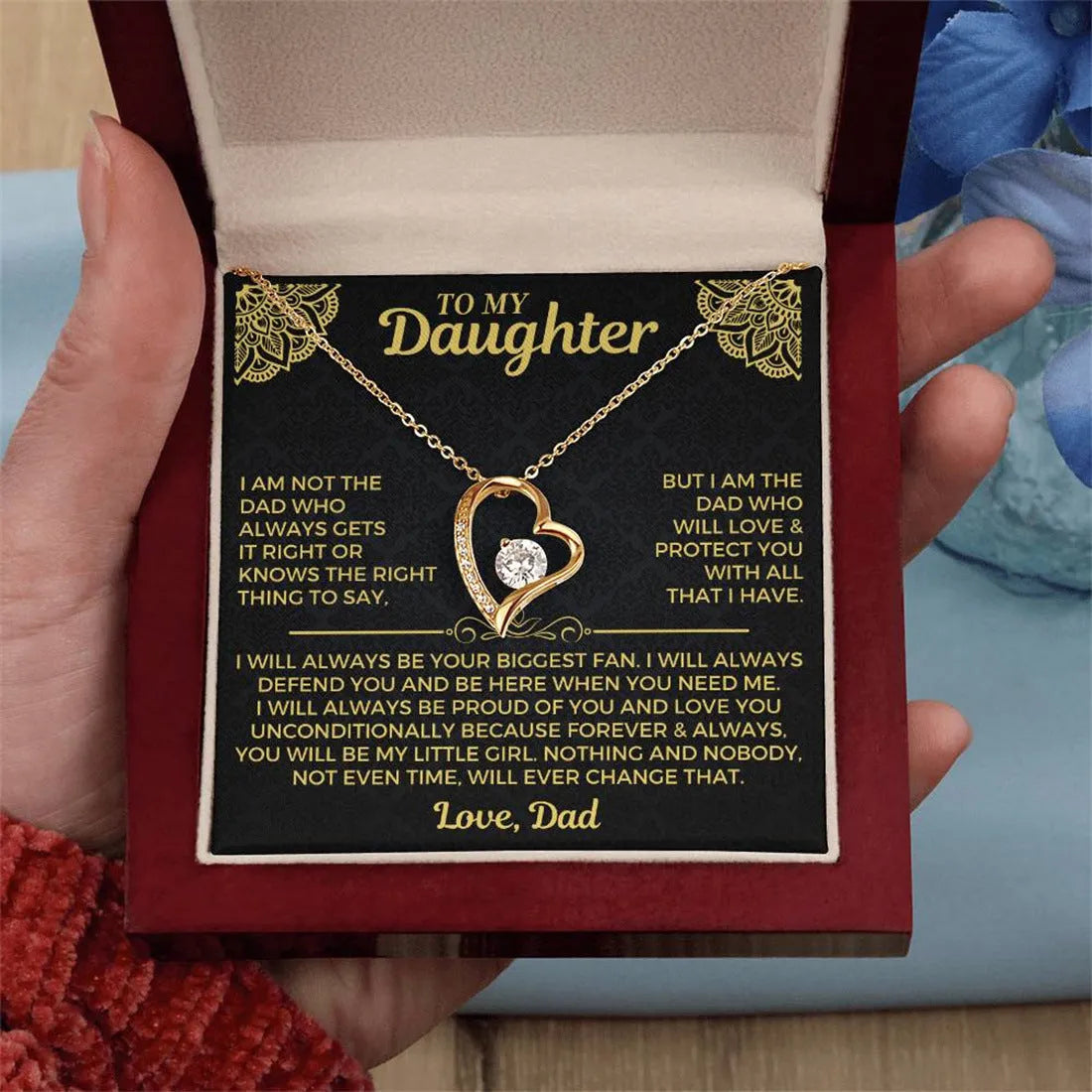 Silver and gold hollow heart necklace pendant presented on a card inside an open gift box.