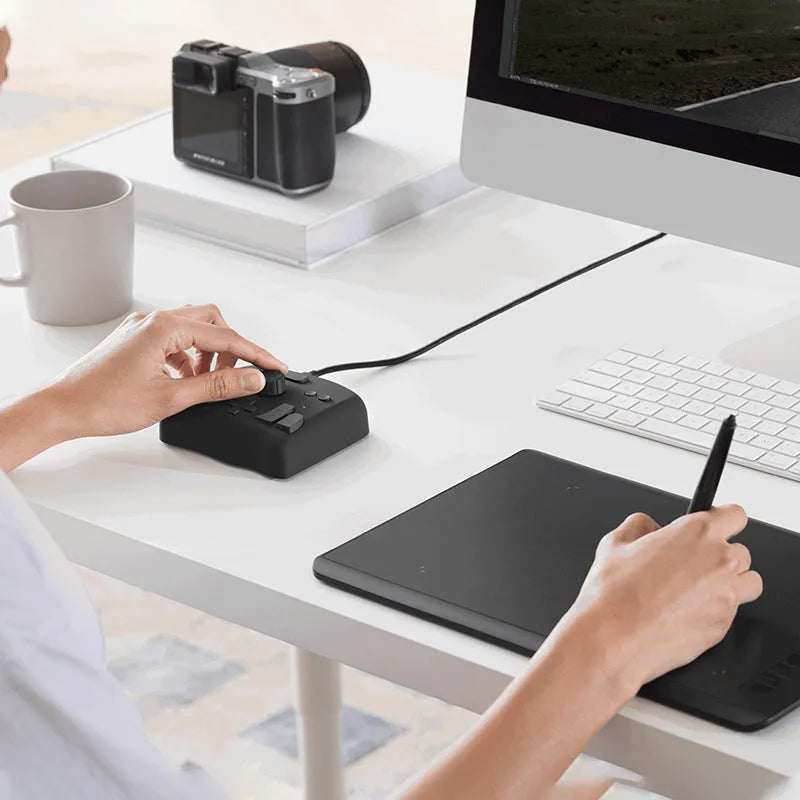 TourBox NEO black USB video editing controller auxiliary keyboard on a desk.