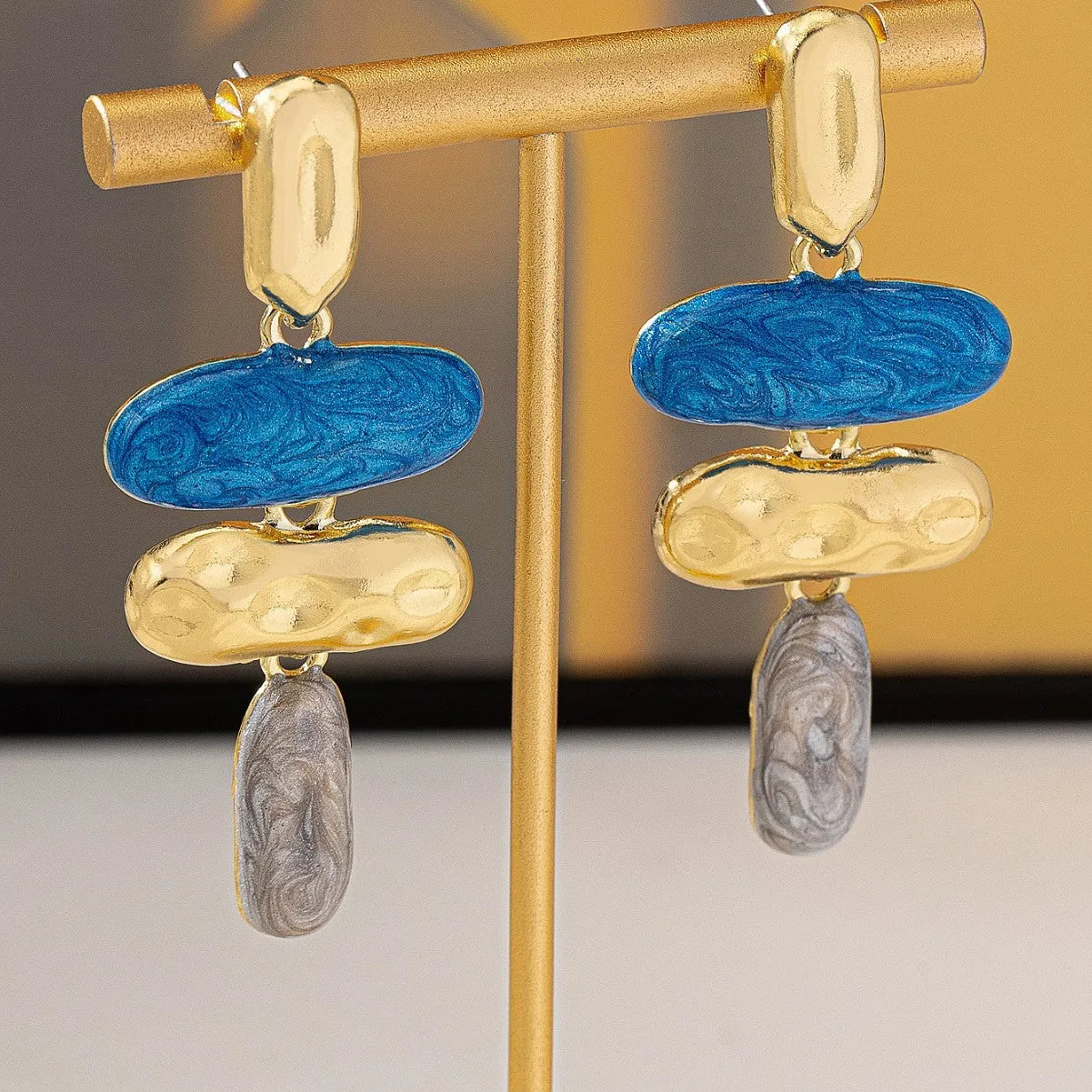 A pair of simple geometric stud earrings with a multicolour electroplated finish on a zinc alloy base.