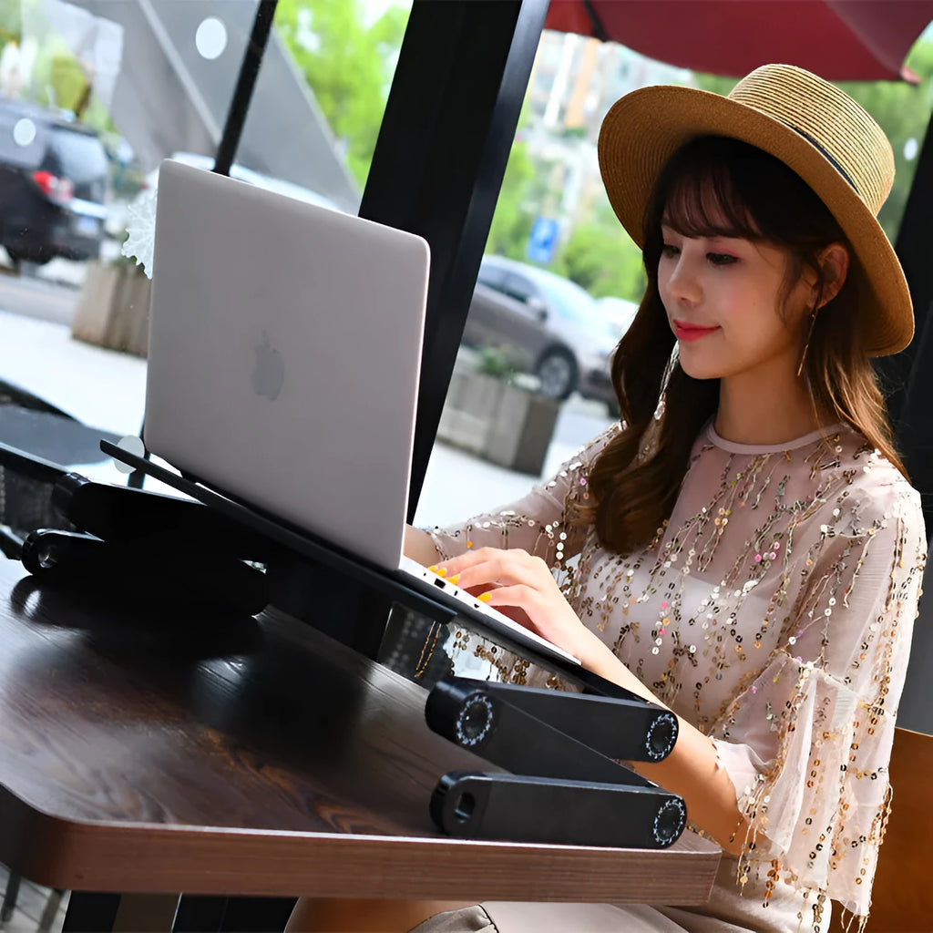 Red folding metal laptop desk with cooling fan and mouse board extended over a bed.