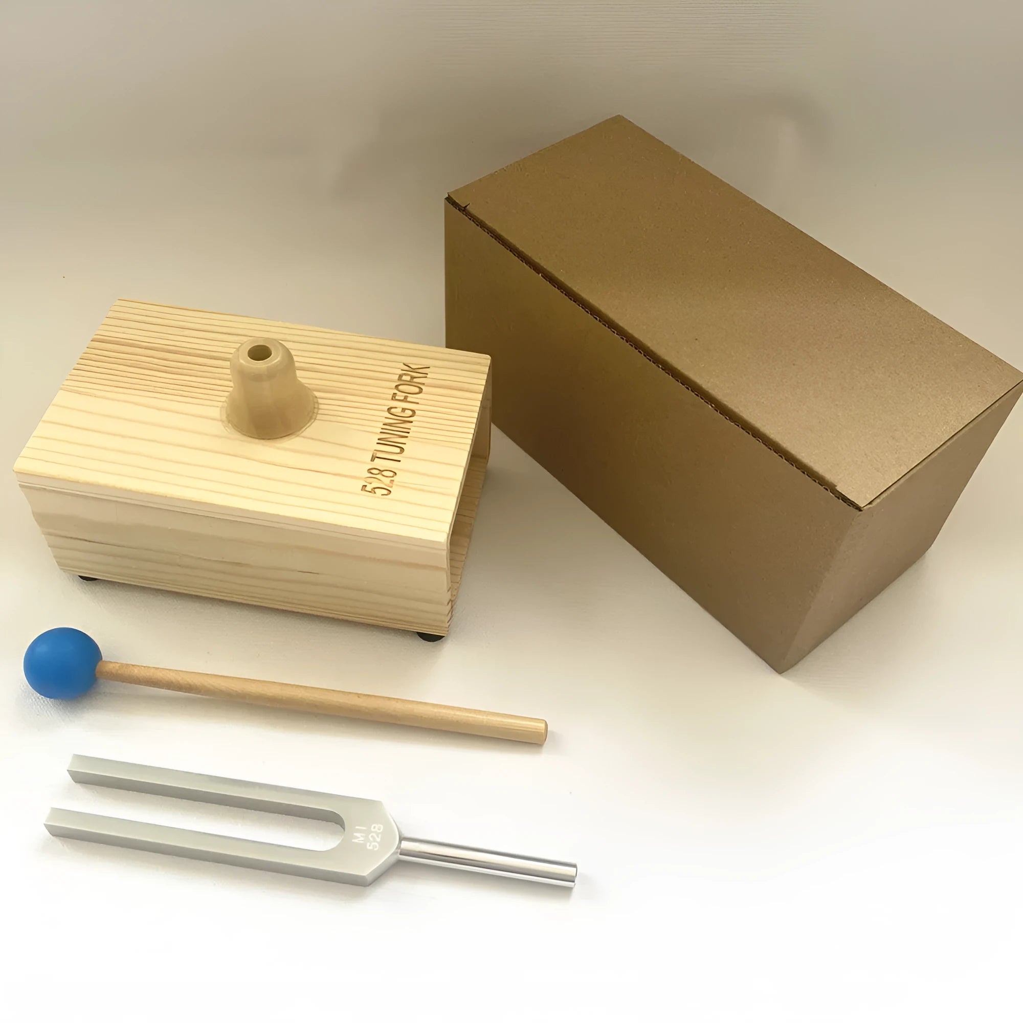 Aluminium alloy 432Hz tuning fork with connected speaker on kraft paper box