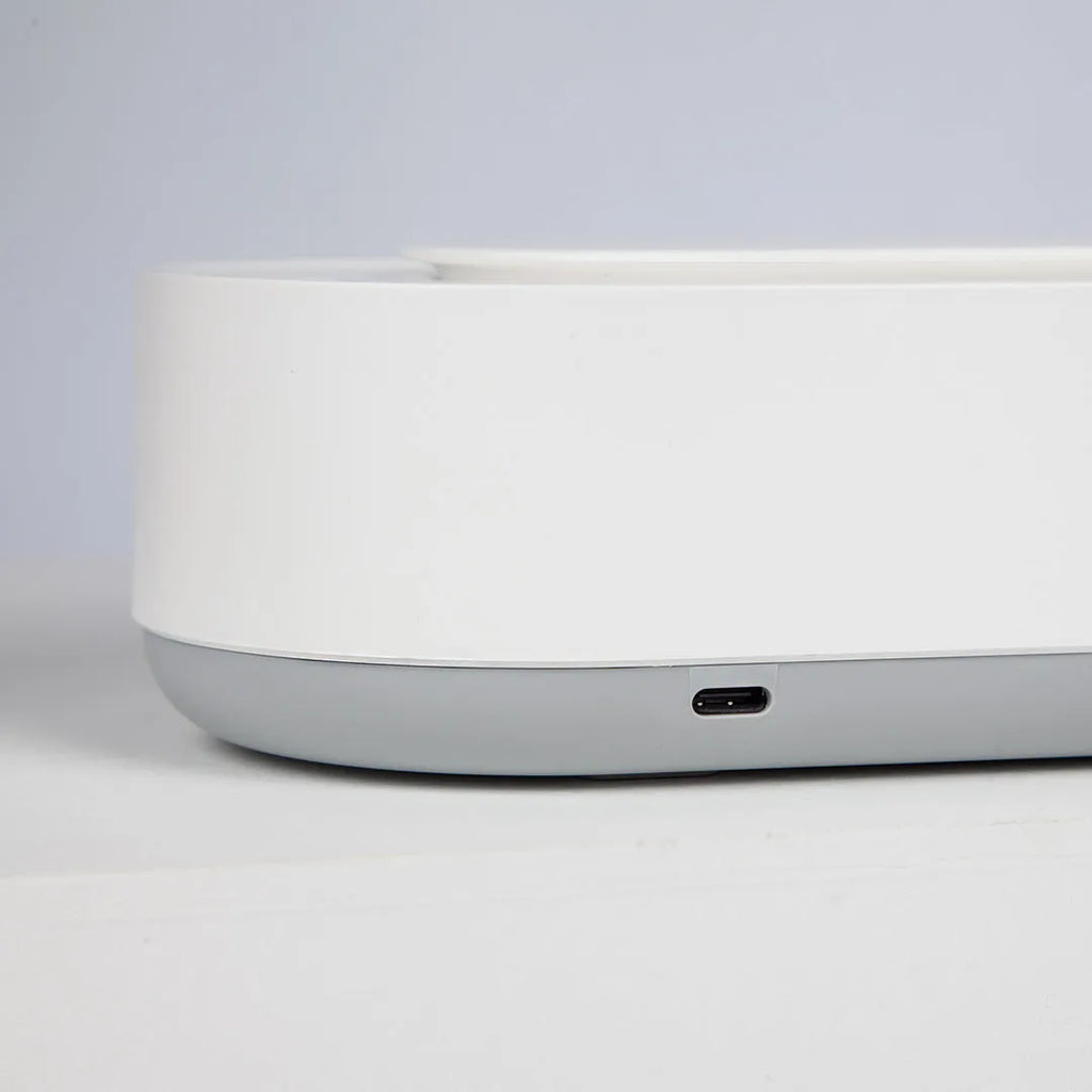 White portable ultrasonic cleaner with stainless steel tank and a single control button.