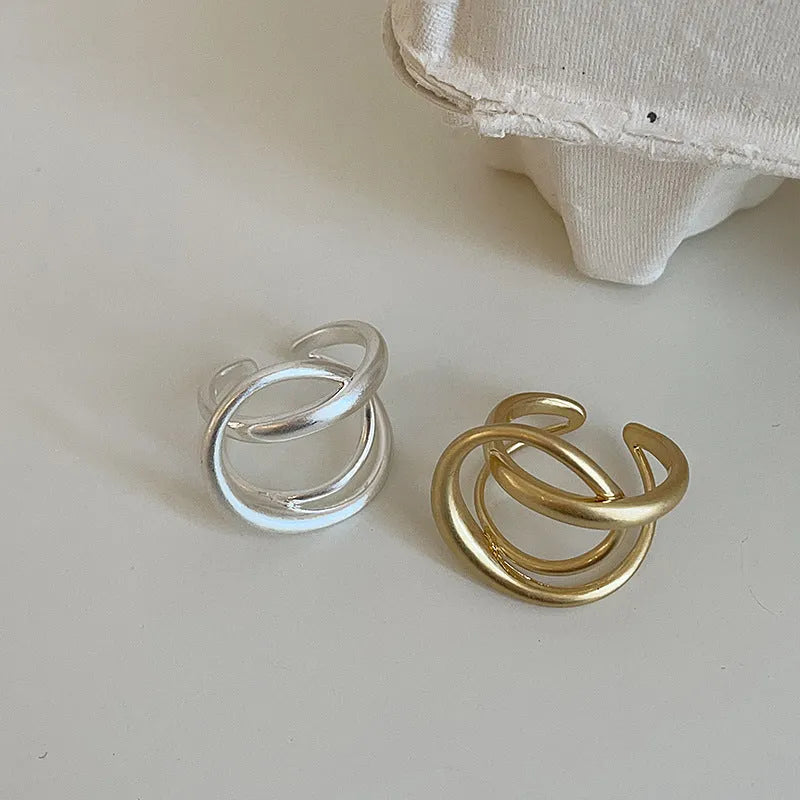 Geometric open ring for women with 3D interlaced matte metal design, shown in gold plating.