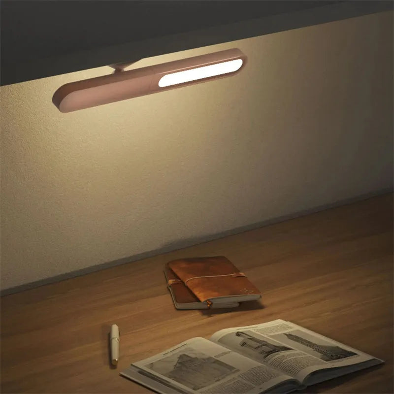 White geometric desk lamp with touch control and magnetic base on a wooden table.
