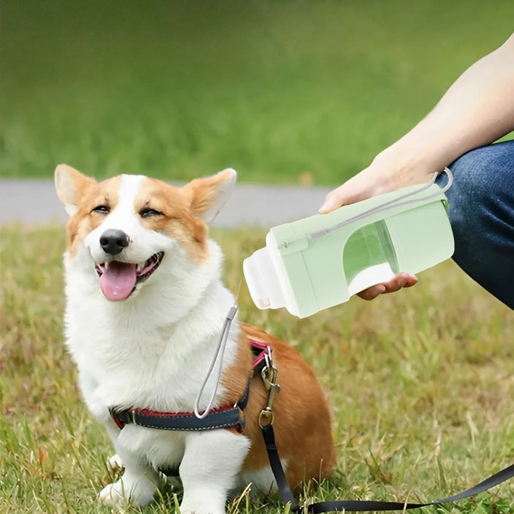 Green portable dog water bottle and feeder with attached lanyard, showing separate food and water compartments.