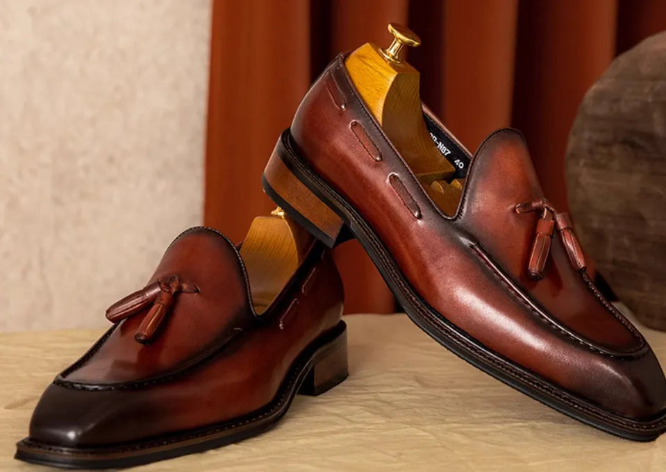Men's black leather slip-on loafers with fringed detailing and polished finish