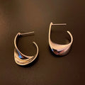 A pair of geometric round earrings with a twisted metal design in a gold electroplated finish.