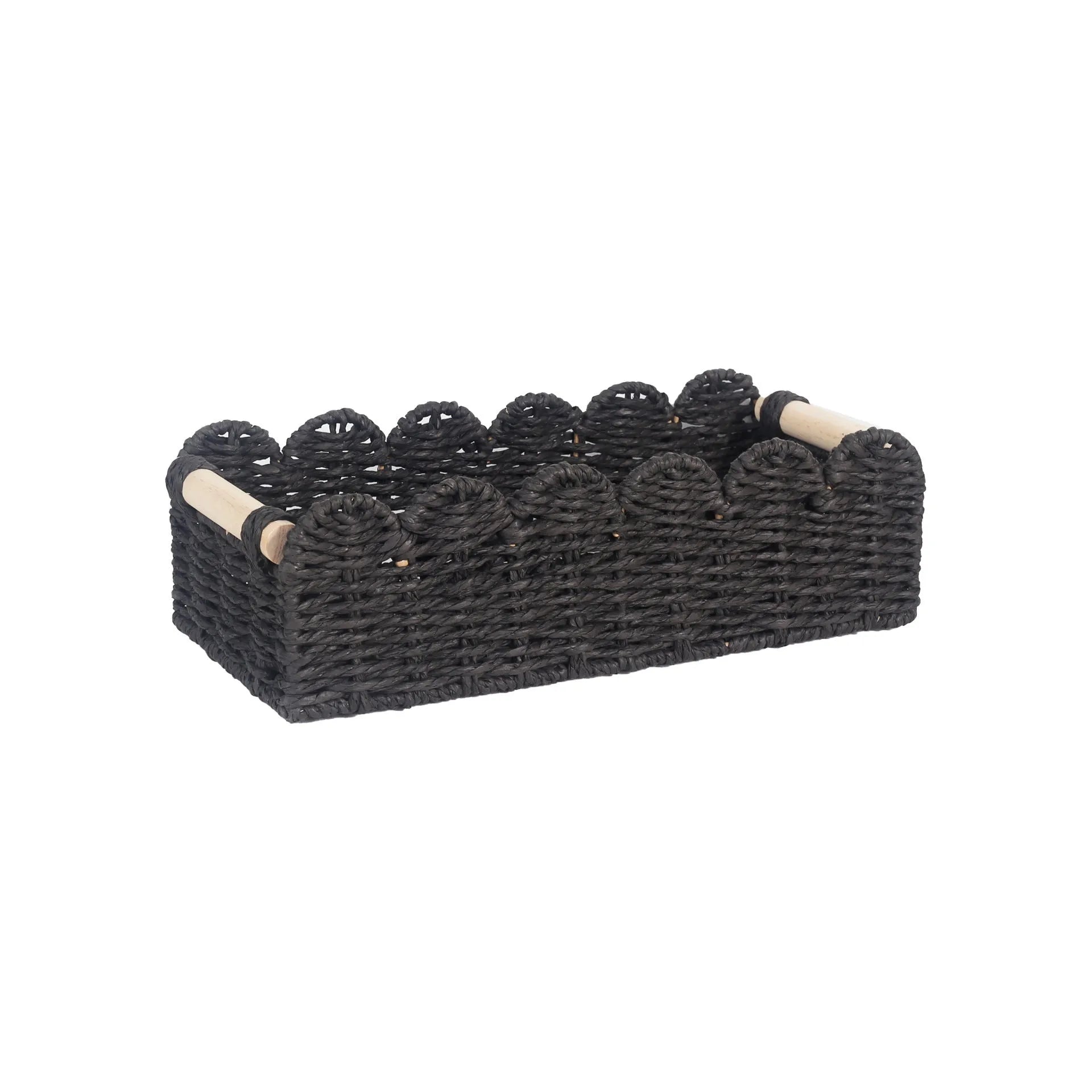 A minimalist woven paper storage basket in khaki colour on a wooden table, holding remote controls and pens.