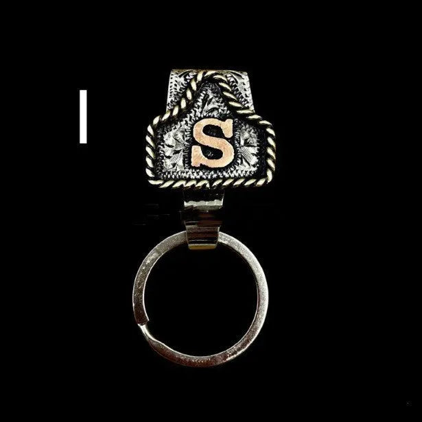 Handmade metal cow tag belt keychain showing one of 26 colour options, each marked with a different alphabet letter.