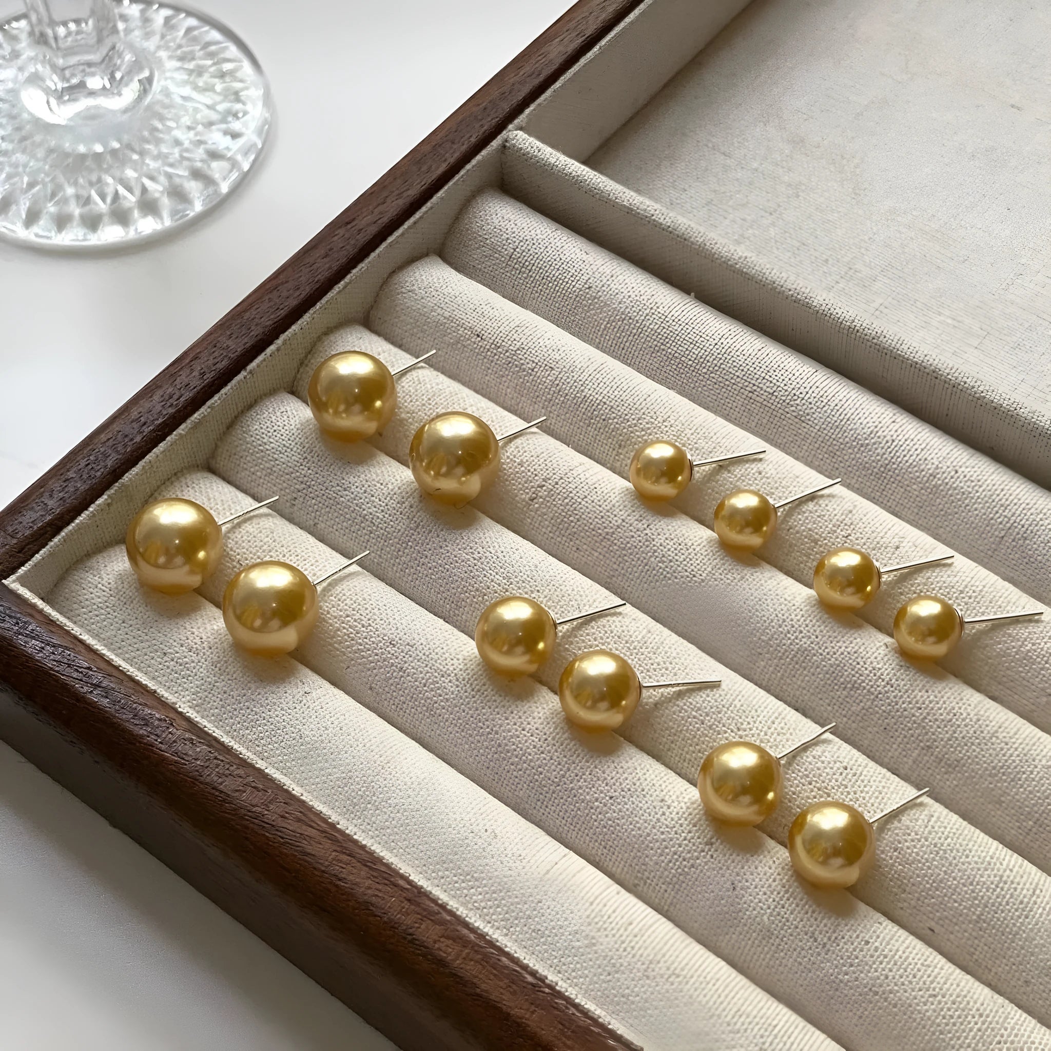 A pair of large pearl stud earrings with a geometric silver setting on a white background.